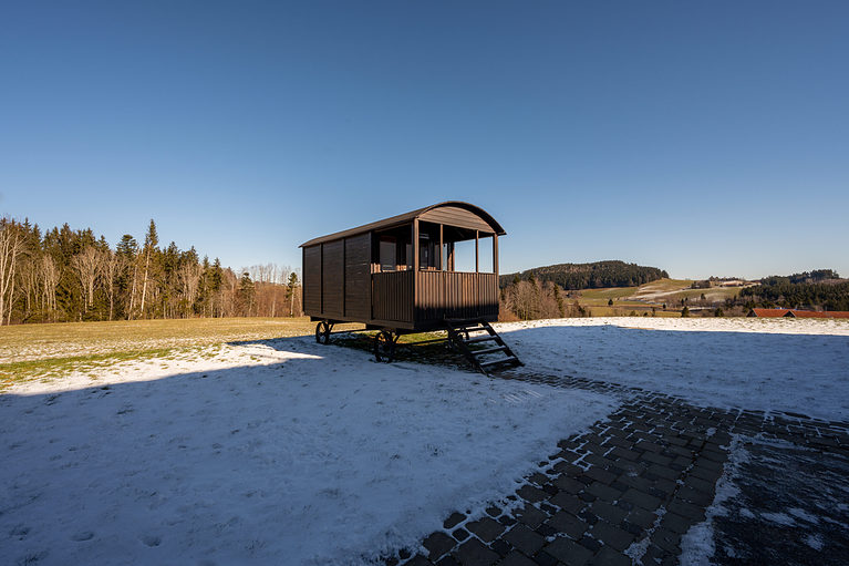 eine kleine Hütte inmitten eines schneebedeckten Feldes.