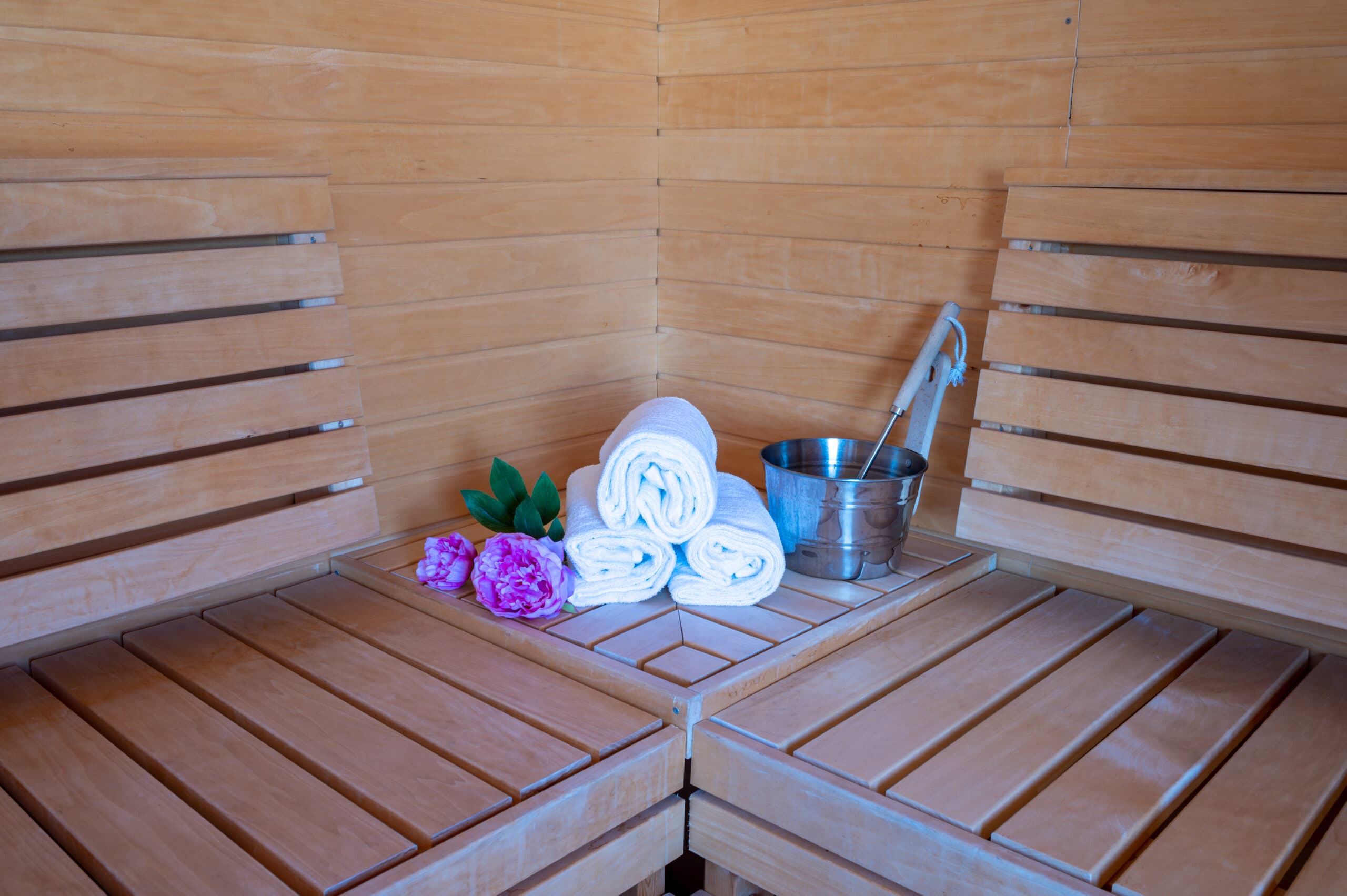 eine Holzsauna mit Handtüchern und einem Eimer Blumen